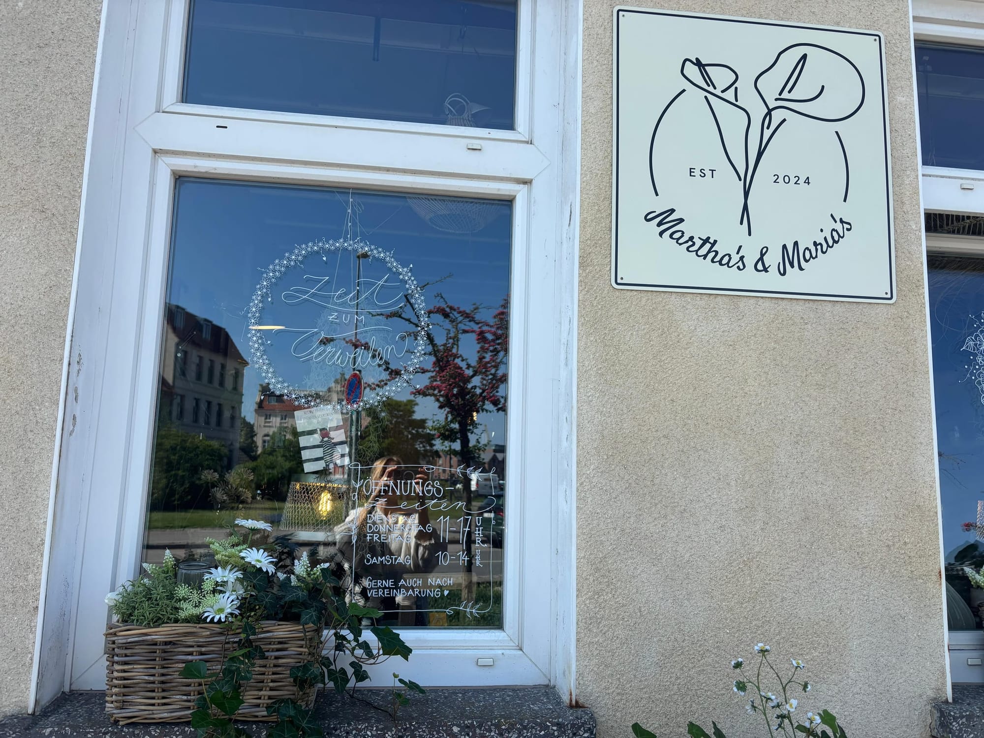 Schaufenster mit Martha's & Maria's Logo — die Wismarer Altstadt spiegelt sich