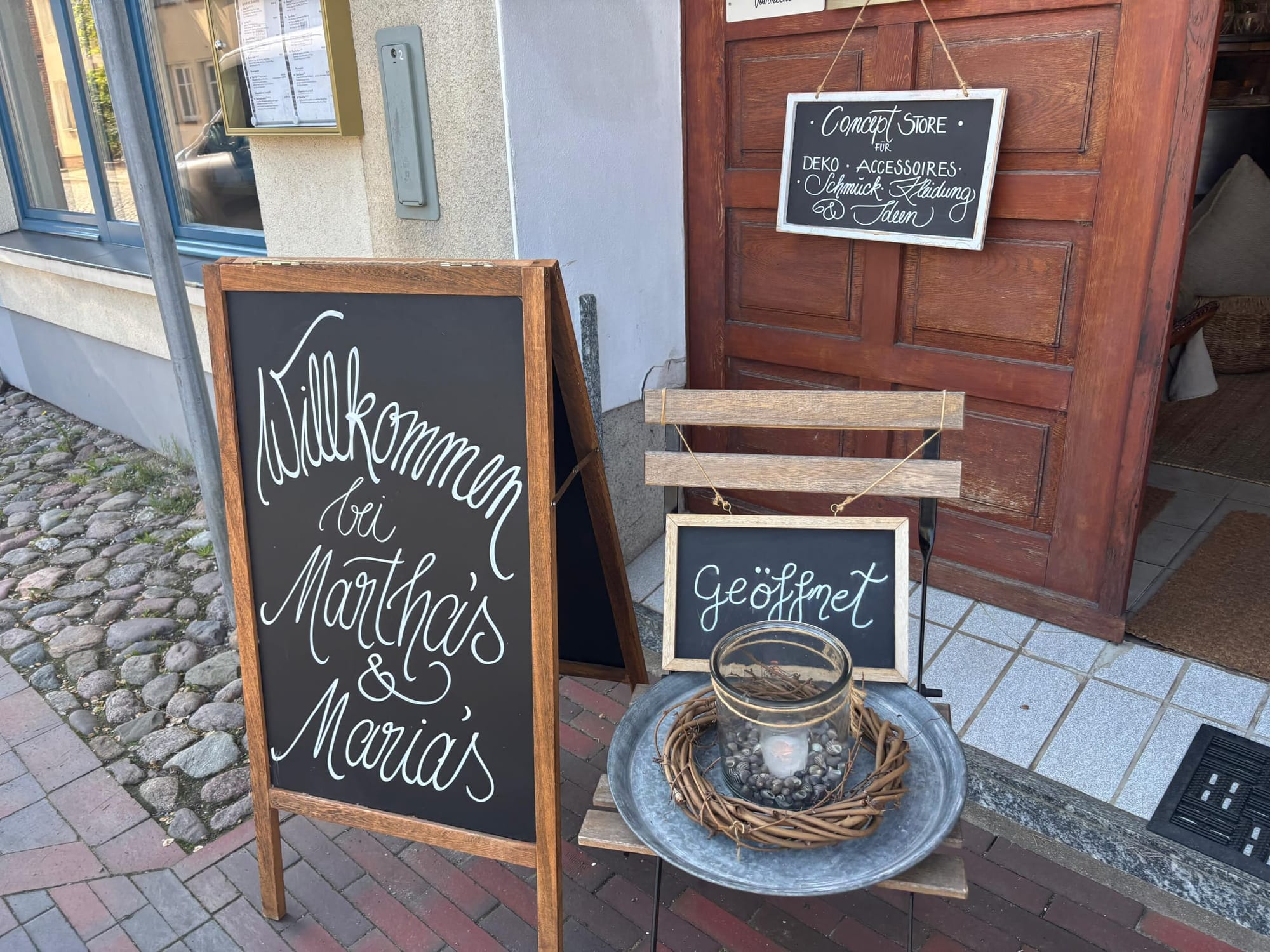 Willkommens-Tafel und Geöffnet-Schild vor der Tür von Martha's & Maria's